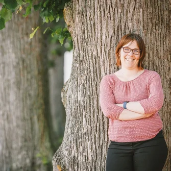 Pastorin Pfeifer lehnt an einem Baum