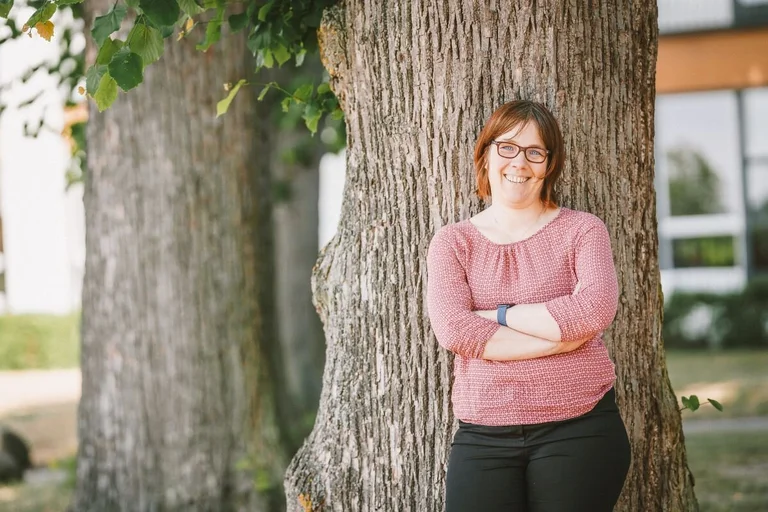 Pastorin Pfeifer lehnt an einem Baum